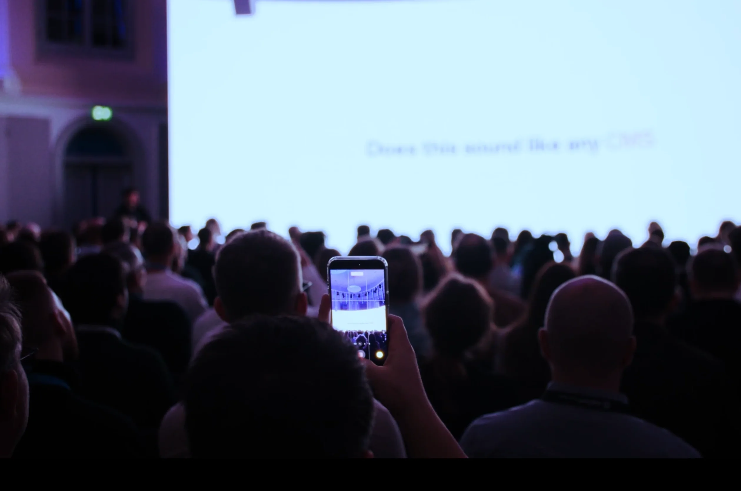 An audience member filming the JoyConf screen on their phone