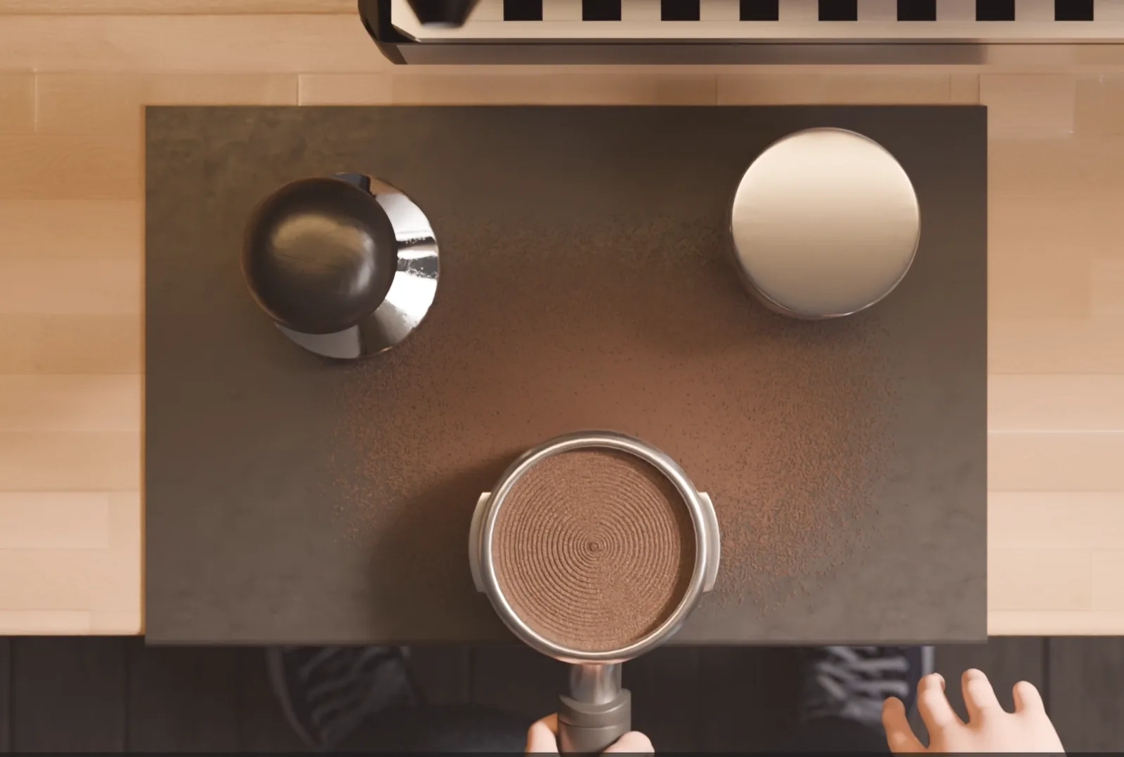 Overhead shot of an espresso portafilter being levelled, grounds scattered on a dark tray.